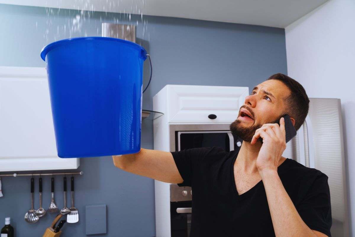 Uomo che usa secchio per tamponare la perdita